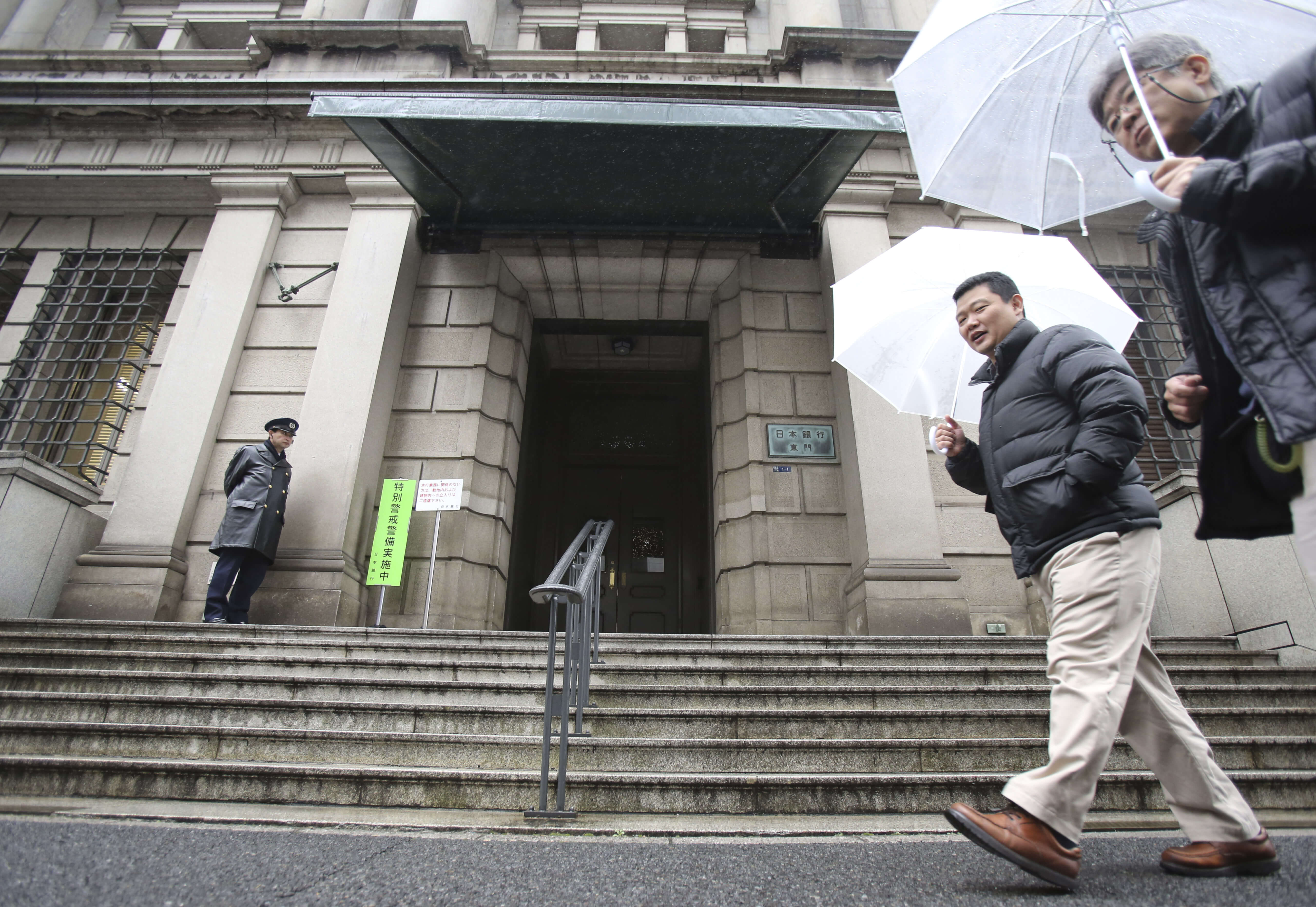 People walk past in front of Bank of Japan Friday, Jan. 29, 2016. The Bank of Japan last Friday introduced a negative interest policy for the first time, seeking to shore up a stumbling recovery in the world's third-largest economy. (AP Photo/Koji Sasahara)