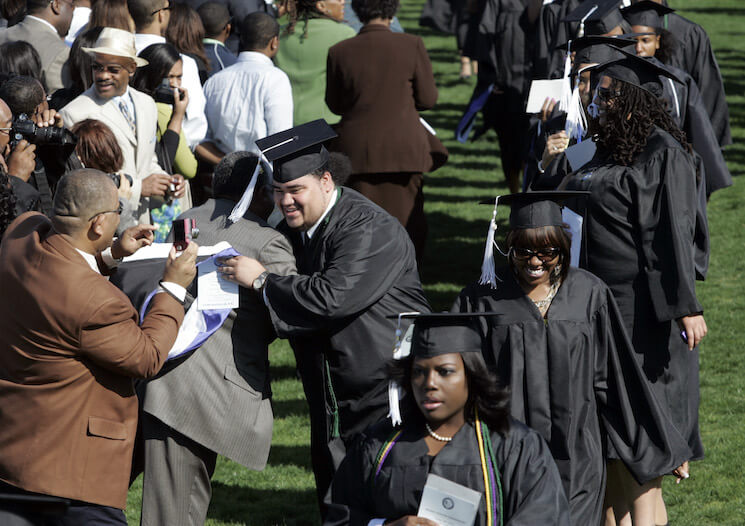 A student hugs family during the procession at commencement ceremonies at Hampton University in Hampton, Virginia. (AP Photo/Steve Helber)