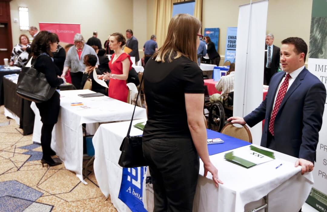 Companies speak with job seekers at a job fair in Pittsburgh, Wednesday, March 30, 2016.