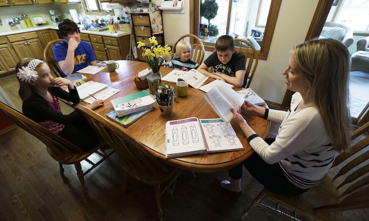 Sara Gustoff, right, reads to her children Abigail, from left, Nathanael, Benjamin, and Jonah while at the kitchen table in their home in Des Moines, Iowa.