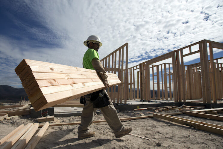 Construction worker Miguel Fonseca carries lumber as he works on a house frame for a new home in Chula Vista, Calif.