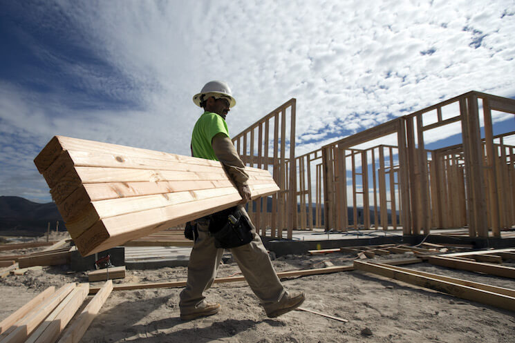 Construction worker Miguel Fonseca carries lumber as he works on a house frame for a new home in Chula Vista, Calif. 