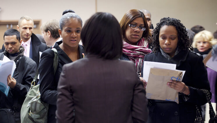People talk with a recruiter, center, at a job fair sponsored by National Career Fairs, in New York. 