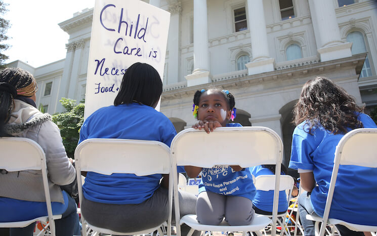 FILE - In this May 6, 2015, file photo Saryah Mitchell, sits with her mother, Teisa, Gay, left, a rally calling for increased child care subsidies at the Capitol in Sacramento, Calif. In much of the U.S., families spend more on child care for two kids than on housing. And if you’re a woman, it’s likely you earn less than your male colleagues even though one in four households with kids relies on mom as the sole or primary breadwinner. 