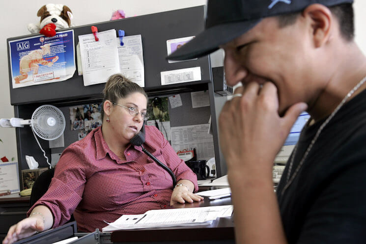 Ayesha Tully, left, responds to call while Larryll Emerson, 20, waits for information pertaining to his next work assignment at the Staffmark temp agency in Cypress, Calif. 