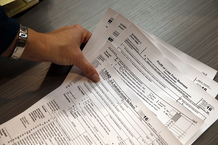 Tax professional and tax preparation firm owner Alicia Utley reaches for hard copies of tax forms.
