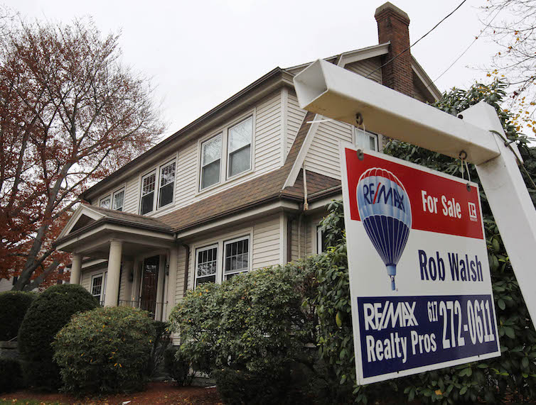 A for sale sign hangs in front of a home, in Milton, Massachusetts. 