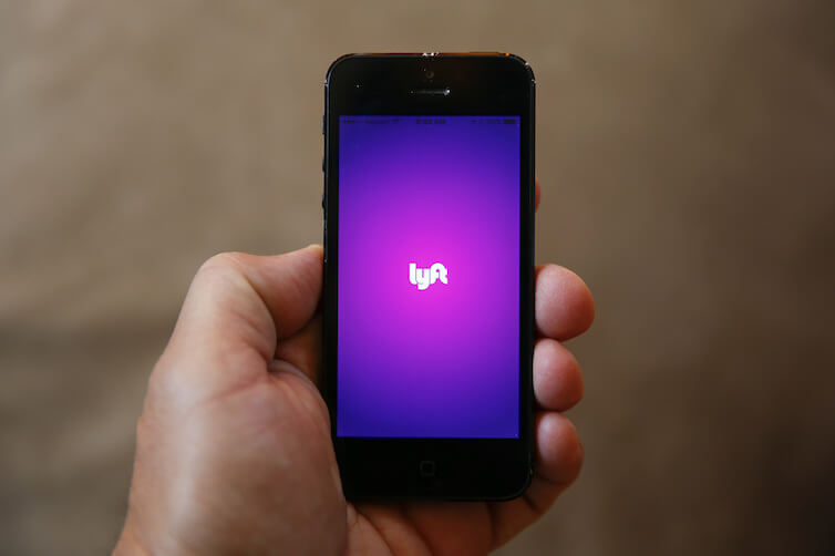A smartphone displaying the Lyft app is shown in Detroit.