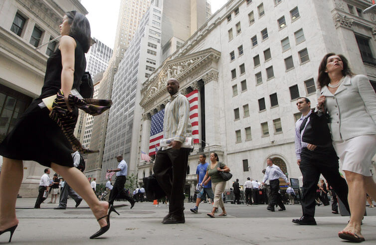 Men and women walk to work on Wall Street in New York.