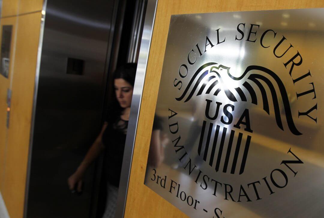 A woman walks past a sign for the Social Security Administration in Los Angeles, July 2011.