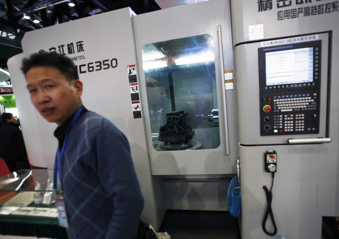 An exhibitor stands near a tool machine on display at an exhibition featuring the science and technology achievement in China at the National Convention Center in Beijing, March 7, 2011.