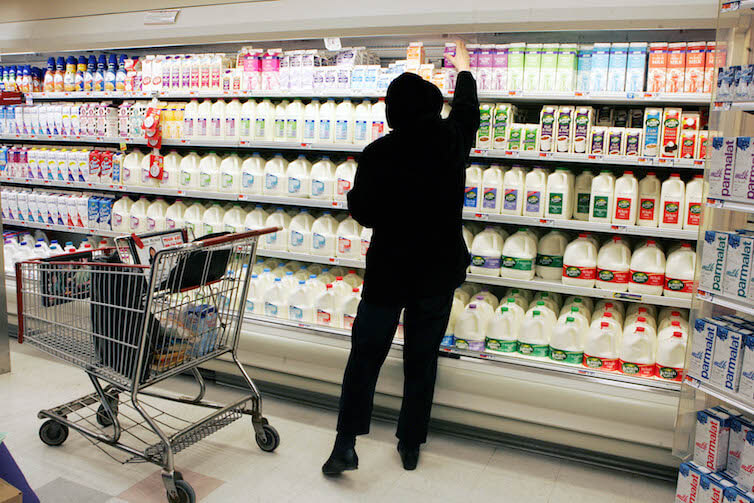 A shopper reaches for a milk product at a supermarket.