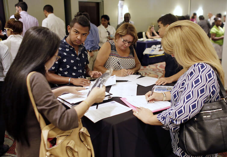 People fill out job applications at a job fair.