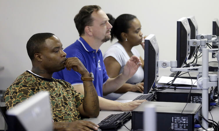 Job seekers look at a computer screens during a resume writing class.