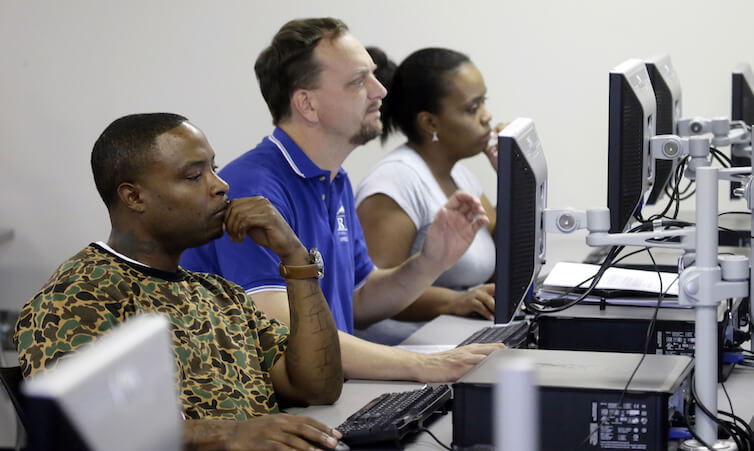 Job seekers look at a computer screens during a resume writing class.  