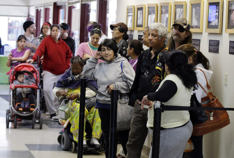 People line up at a food pantry at Sacred Heart Community Service in San Jose, CA.