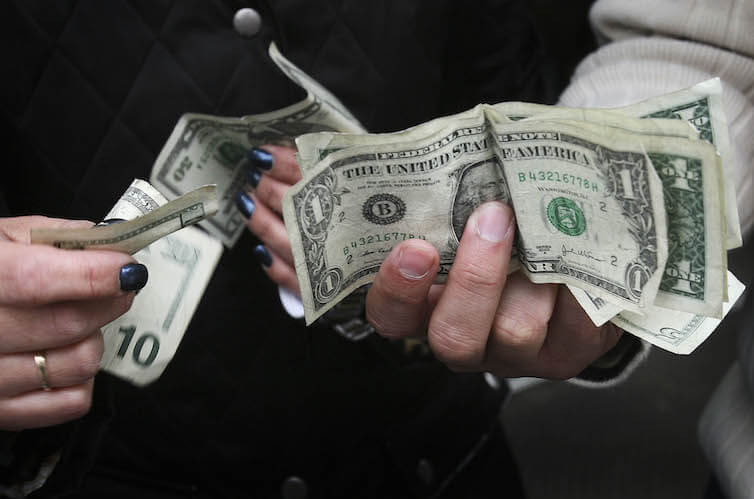 Two shoppers make change for a purchase on Canal Street in New York. 