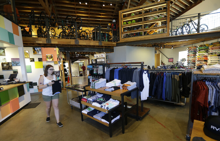 A retail employee folds shirts for display on the main-floor area of a Seattle-based outdoor, bike, ski, and clothing company. 