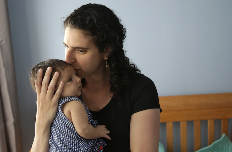 Elena Tenenbaum kisses her eight-week-old baby Zoe at their home in Providence, Rhode Island. Tenenbaum has been able to use Rhode Island’s paid family leave program, which started in 2014 and covers four weeks of partial pay.