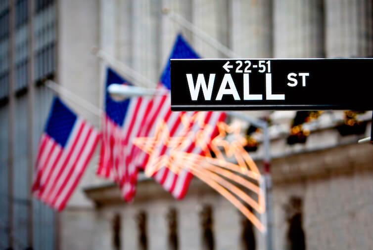 Wall Street sign, with the New York Stock Exchange in the background. A new working paper studies the benefits to businesses of lobbying by looking at the participation of financial institutions in the rulemaking process after the enactment of Dodd-Frank.