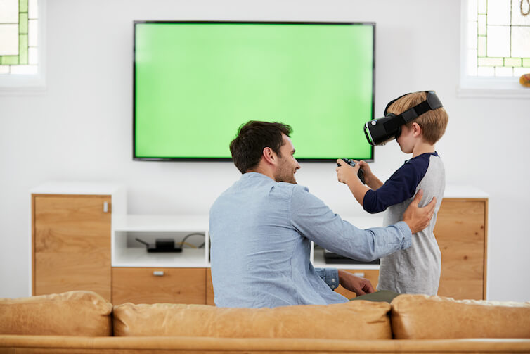 A father and son play with a virtual reality headset. A new study shows that sons are more likely to start their own businesses if their fathers are entrepreneurial.