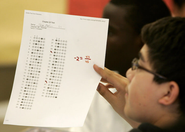 A KIPP charter school student holds up a practice test during class in Houston.